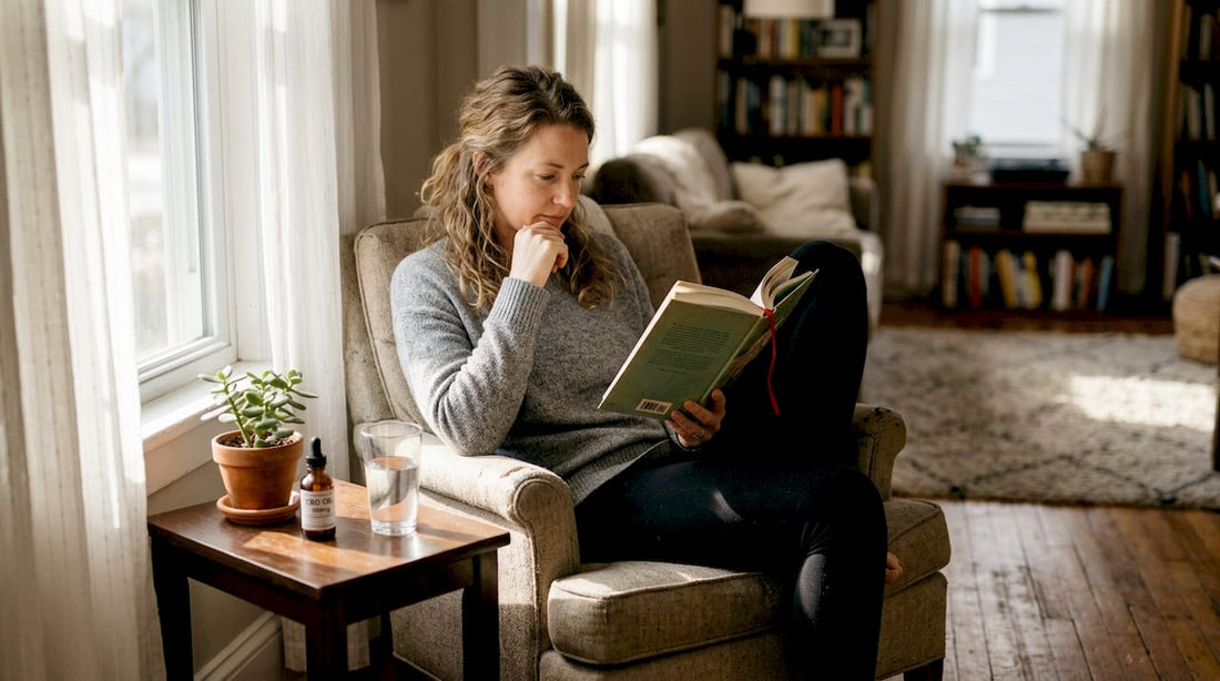Woman reading book with CBD oil on table