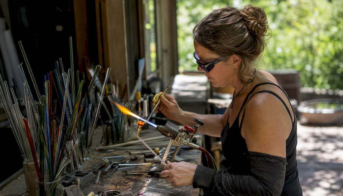 Glass pipe artist shaping molten glass at bench