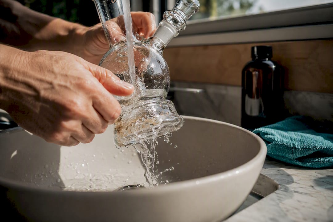 Hands rinsing an anonymous glass bubbler